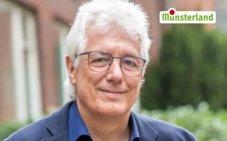 Porträt von Manfred Fleige vor einer Backsteinfassade, oben rechts das Münsterland Logo